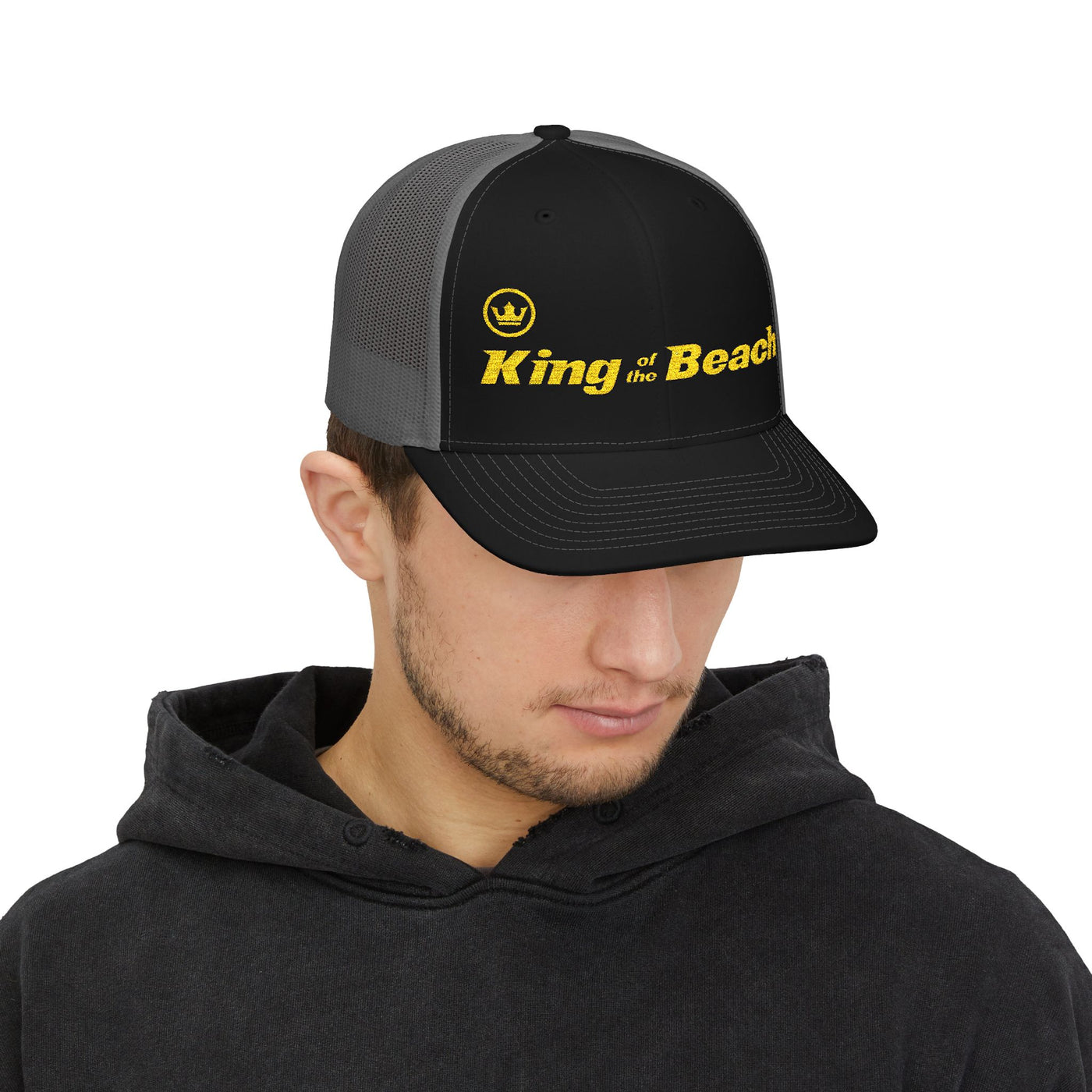 Person wearing a black and gray cap with 'King of the Beach' text on a white background