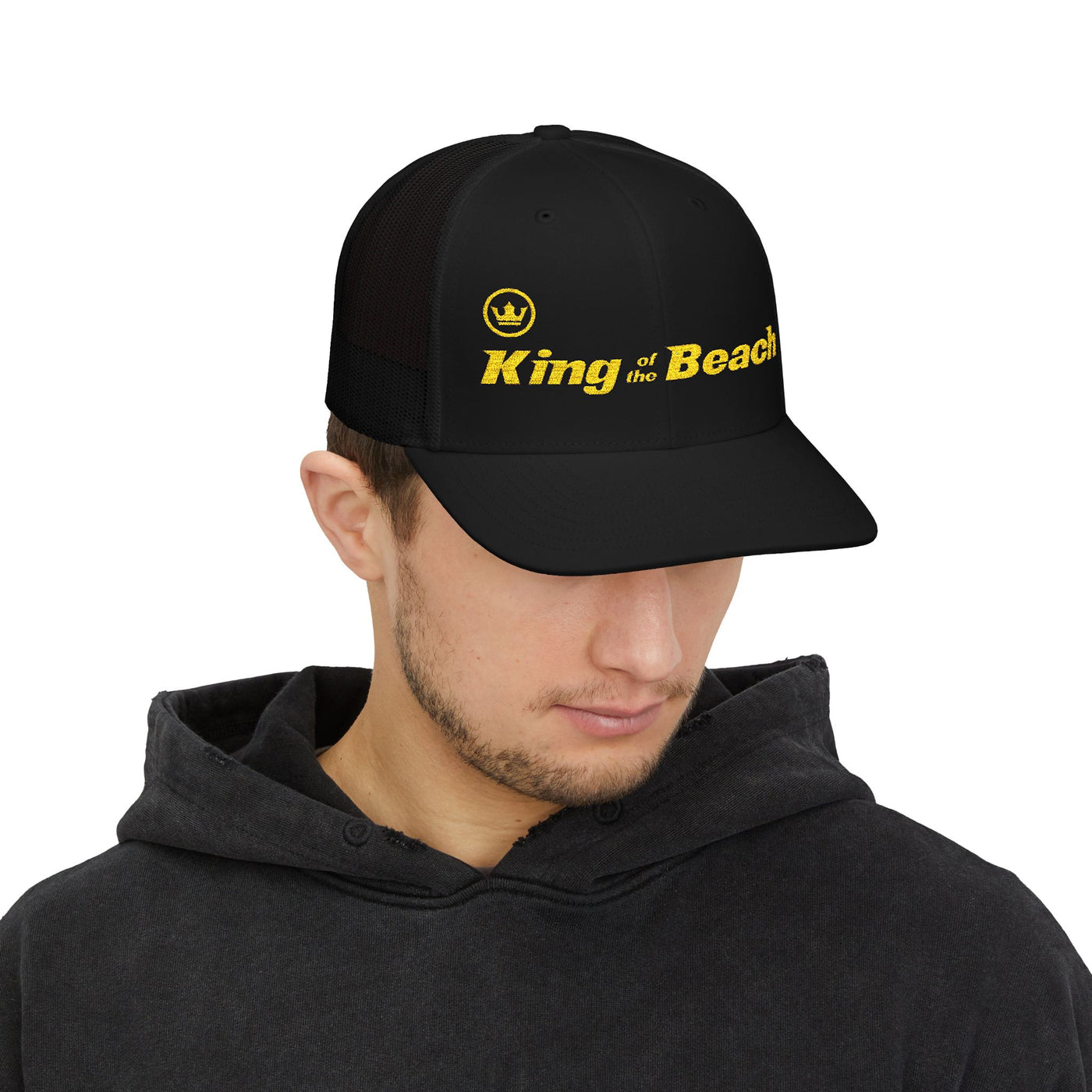 Person wearing a black cap with 'King of the Beach' text on a white background