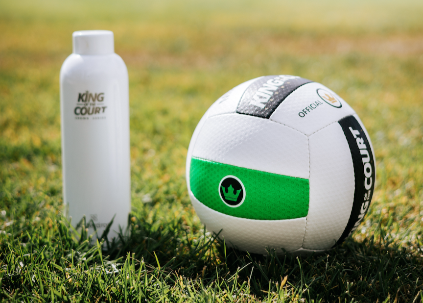 White and green KING OF THE COURT Grass volleyball with a King of the Court bottle on grass
