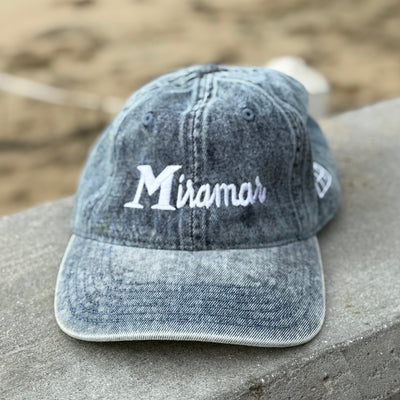 blue cap with 'Miramar' logo on a stone surface with a blurred natural background