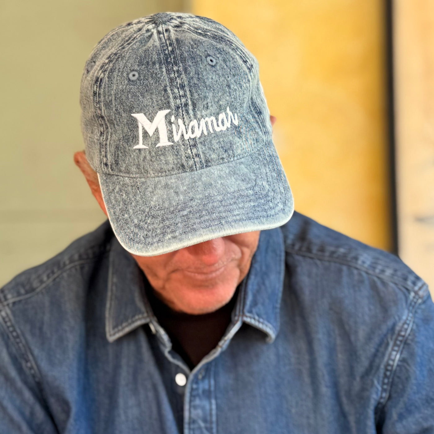 Man wearing a denim cap with 'Midamer' embroidered on it against a neutral background